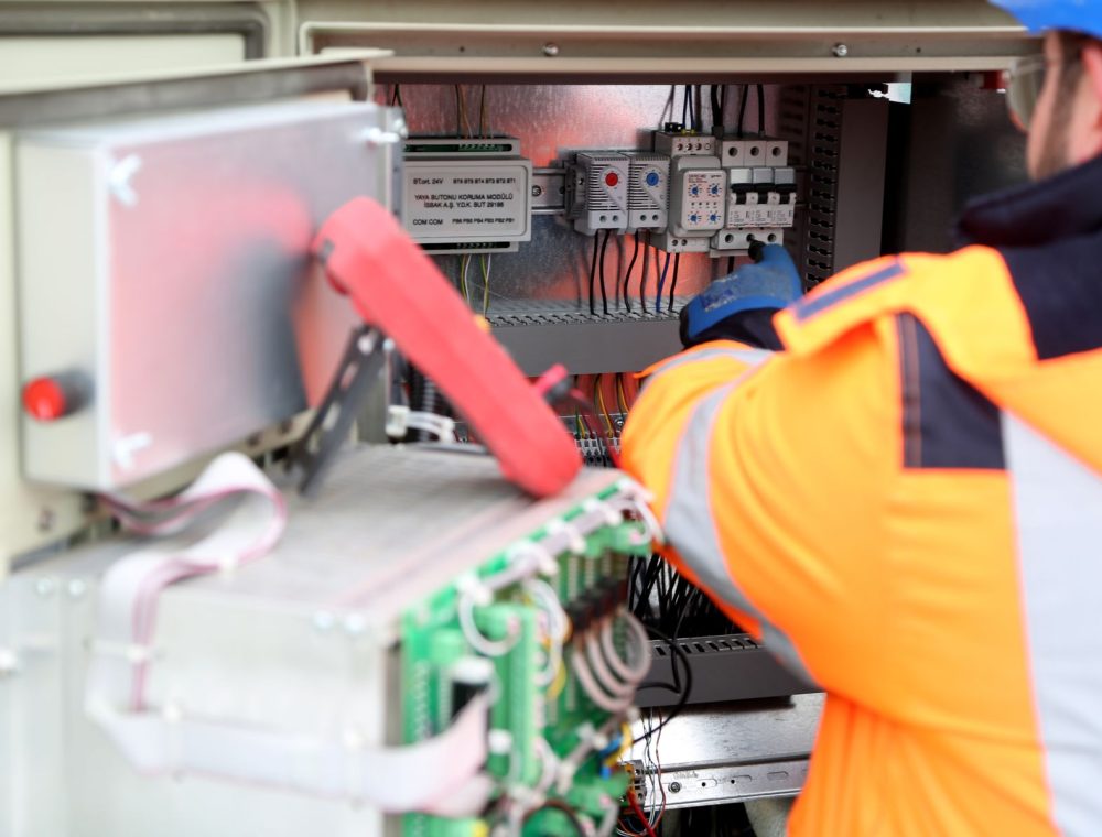 Elektriker in Warnjacke arbeitet an einer Schaltanlage