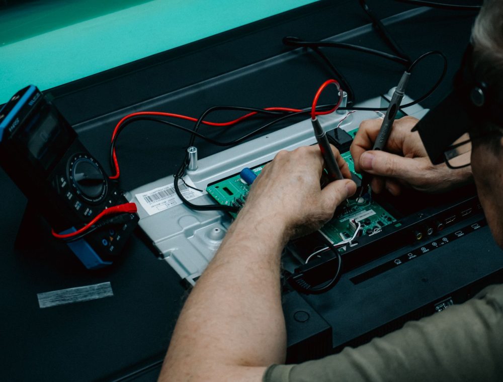 Hände messen mit dem Multimeter an einer Elektronikplatine